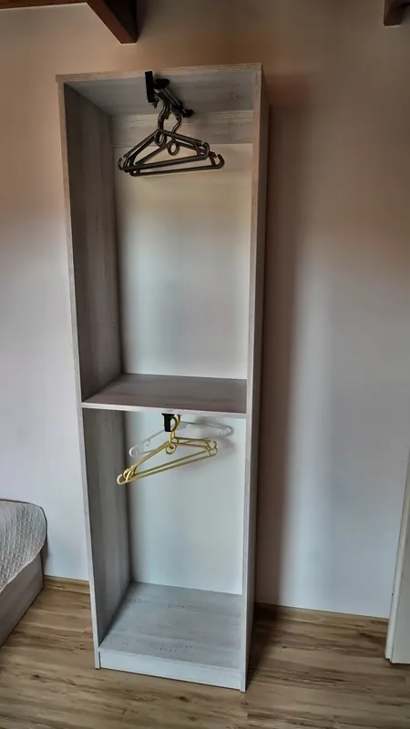 Otwarta szafa z wieszakami w sypialni trzyosobowej